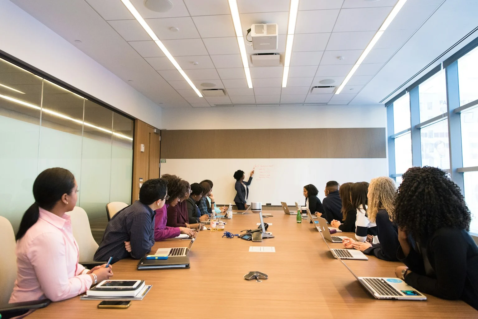 A team watching a colleague outline work on a whiteboard.